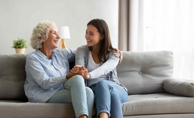 elderly women on her couch at home with a visitor