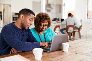 man visiting senior in her home helping with computer