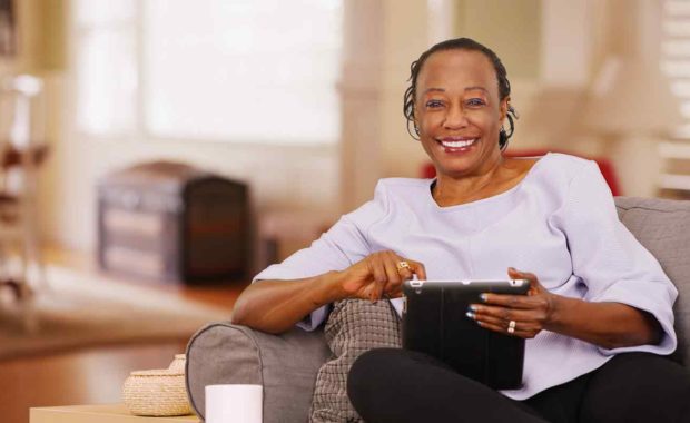 senior women at home reading the news from her tablet