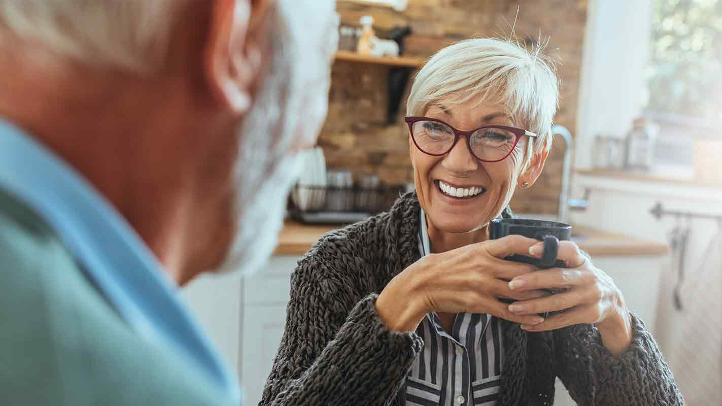 Senior woman holding mug smiling at senior man