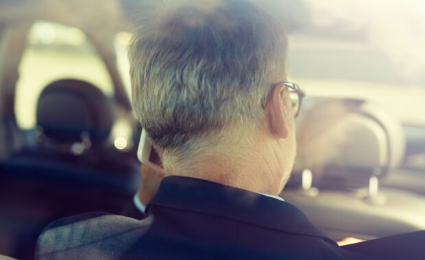 senior businessman calling on smartphone and driving on car back seat