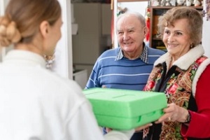 women delivering meal to old couple