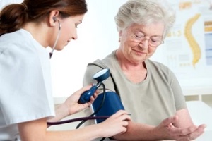 female doctor checking blood pressure of old women