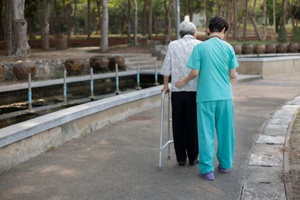 old female train use walker with health worker while Aging In Place 
