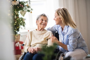 senior woman in wheelchair with a health visitor at home at christmas time