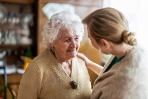 health visitor part of a Friendly Visitor Program talking to a senior woman during home visit