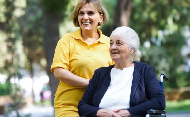 helpful caregiver and handicapped senior woman