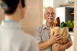 elderly man receiving grocery delivery at front door