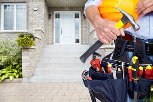 handyman who works for a home repair program in front of a home with tool belt