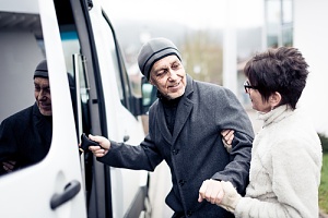 senior transportion volunteer helping an elderly man