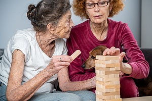 middle aged women volunteer playing with elderly women