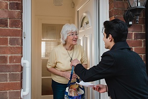 young male volunteer delivering groceries to elderly women