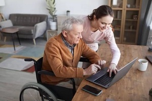women telling old man how to use laptop