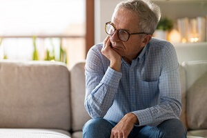 worried senior man sitting alone in his home