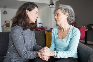 elderly woman and her daughter talking and holding hands