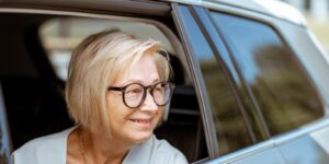 happy senior business woman looking out the car window