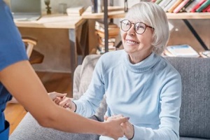 female professional caregiver taking care of elderly woman at home