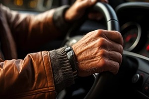 close-up of hands of an older man driving a car