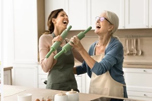 older mom and excited adult daughter having fun in kitchen