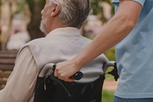 woman pushing wheelchair with senior man