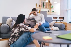 young women with drinks resting at home discussing parents getting older