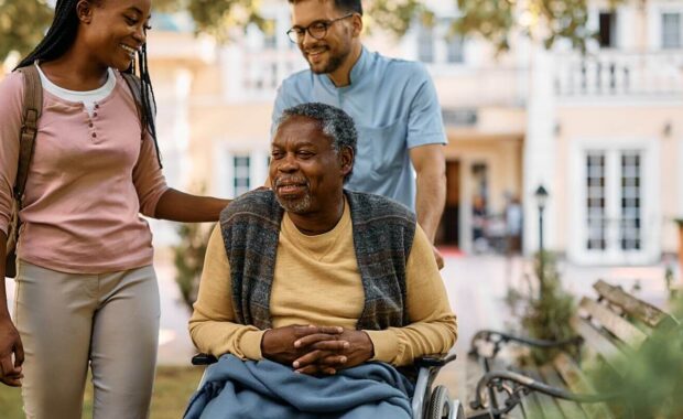 happy black woman visiting her senior father in nursing home