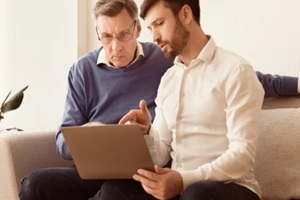 mature man teaching old dad to use laptop