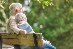 elderly couple resting on a bench in the park