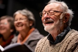 old man smiling while talking to his friends