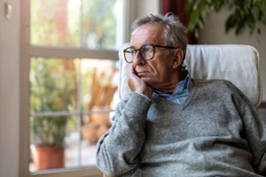 alone senior man sitting and looking out of window