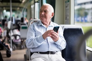 old man sitting in bus and using phone