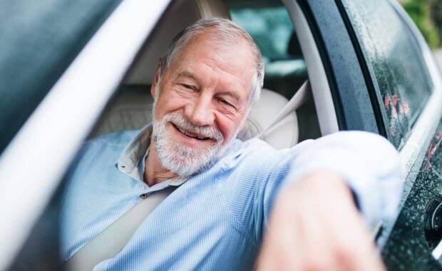 happy senior man sitting in car in driver seat