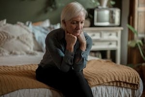 Sad Old Woman Sitting on Bed