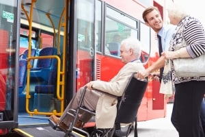 Driver Helping Senior Couple Board Bus Through Wheelchair