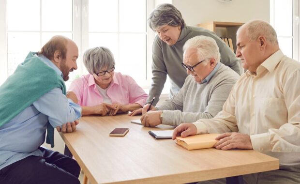 cheerful retired friends sitting around table at home