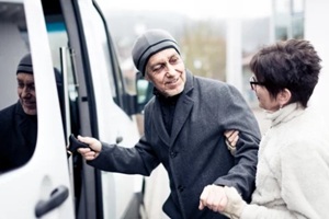 nurse helping senior man enter a van