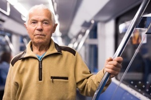 old man standing in subway car